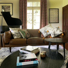 Load image into Gallery viewer, soft paperbark and butterflies in grey, yellow and beige neutrals printed on square linen designer cushions on a leather lounge in piano room