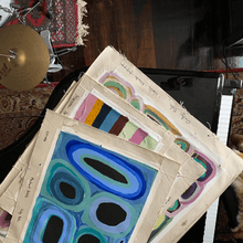 Load image into Gallery viewer, colourful indigenous paintings on a black baby grand piano next to a drum kit