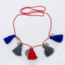 Load image into Gallery viewer, Ethically sourced Old Fashioned Online multi coloured red beaded necklace with blu, grey and red tassels and five silver amulet charms on flat lay