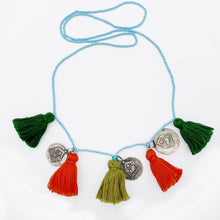 Load image into Gallery viewer, Ethically sourced Old Fashioned Online blue beaded necklace with green and orange tassels and five silver amulet charms necklace on flat lay