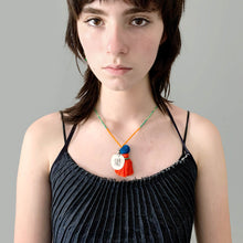 Load image into Gallery viewer, Colorful Old Fashioned Online green and orange beads with tassel, pompom and silver amulet charm in pink and blue on girl wearing blue denim