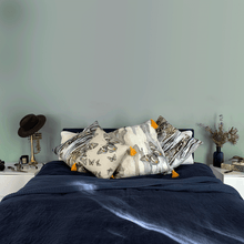 Load image into Gallery viewer, soft paperbark and butterflies in grey yellow and beige neutrals printed on square linen designer cushions on a navy blue linen bed in a bedroom with sage walls