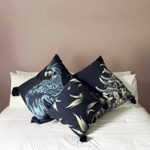 Load image into Gallery viewer, printed eucalyptus gumleaf on blue square linen designer cushion with tassels and handmade in Australia on a white bed in a room with terracotta walls