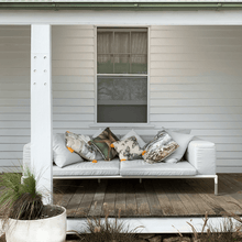 Load image into Gallery viewer, soft paperbark and butterflies in grey, yellow and beige neutrals printed on square linen designer cushions on a lounge on the veranda of a victorian farm house