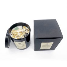 Load image into Gallery viewer, A picture of a large white candle sprinkled with flower petals and a crystal imbedded in it next to the box it comes in.