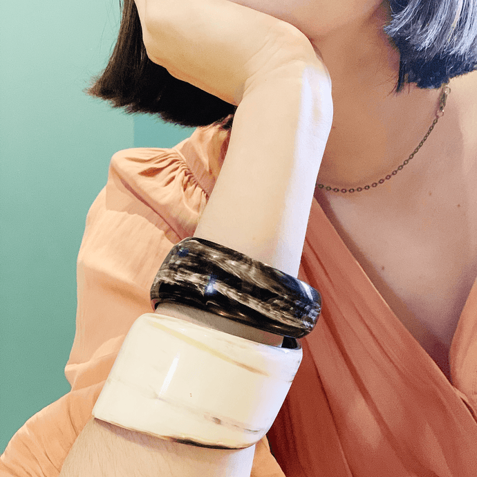 girl in peach dress wearing large horn bracelet and simple gold chain